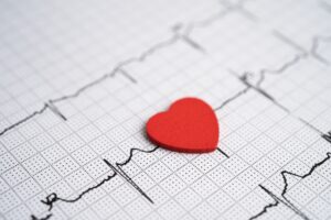 Red heart placed on an electrocardiogram showing heartbeat lines